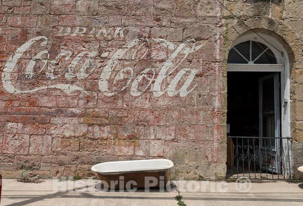 Photo - Faded Coca-Cola Sign on The Side of The Emporium Western-wear Store, and Above an incongruous Sidewalk Bathtub, in Gonzales, Texas- Fine Art Photo Reporduction